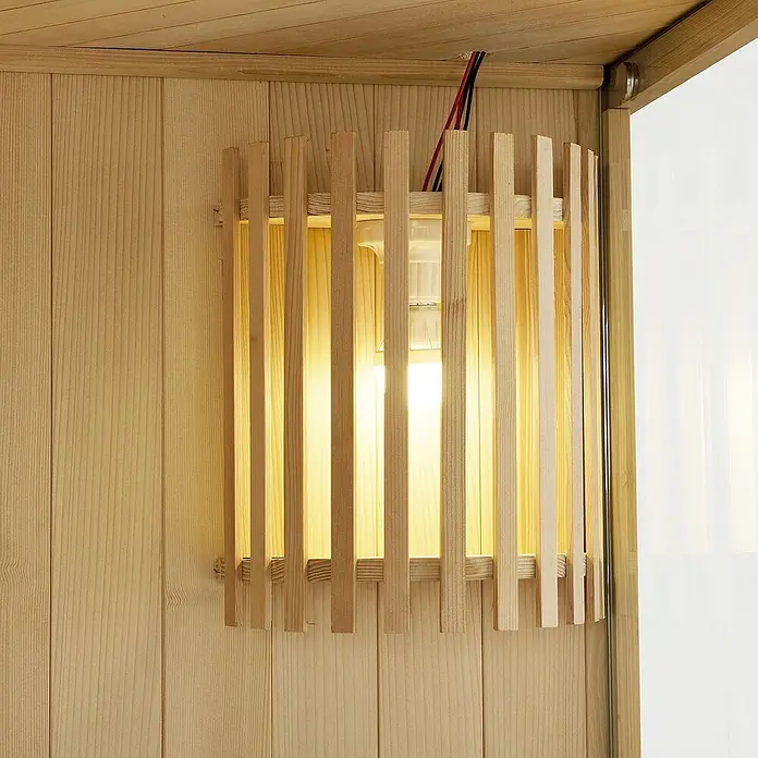 Artsauna Elementsauna Espoo - L x B x H: 150 x 150 x 200 cm - Helle Holzlampe mit vertikalen Lamellen, die ein warmes Licht abgibt, an einer Holzwand montiert.
