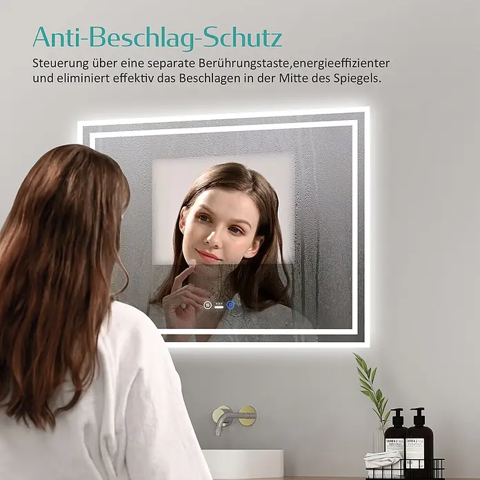 Emke Lichtspiegel Dimlite LM04 - 70 x 50 cm - Beleuchteter Badezimmerspiegel mit Antibeschlagfunktion, zeigt ein klares Spiegelbild einer Frau, während die Ränder beschlagen sind.