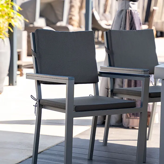 Home Deluxe Sitzauflage MADERA Sitzkissen - 6er Set - 6 Stk., L x B x H: 41 x 42,5 x 3,5 cm, 100% Polyester, Anthrazit - Zwei graue Outdoor-Stühle mit dunkelgrauen Kissen auf einer Terrasse. Die Metallgestelle haben Armlehnen.