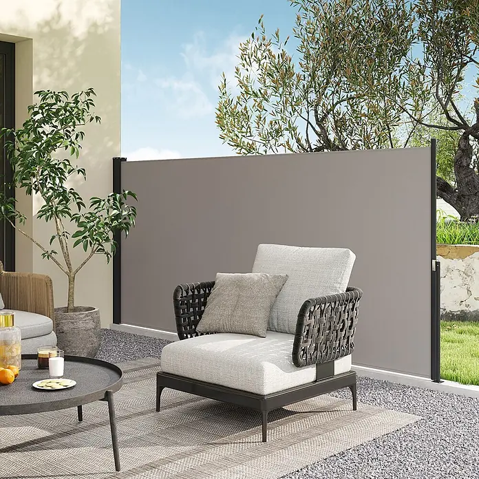 Outsunny Sichtschutzelement - Metall, Hellgrau - Ausgezogene graue Seitenmarkise auf einer Terrasse, die Privatsphäre für Sitzgelegenheiten im Freien mit geflochtenen Stühlen und einem Couchtisch bietet.
