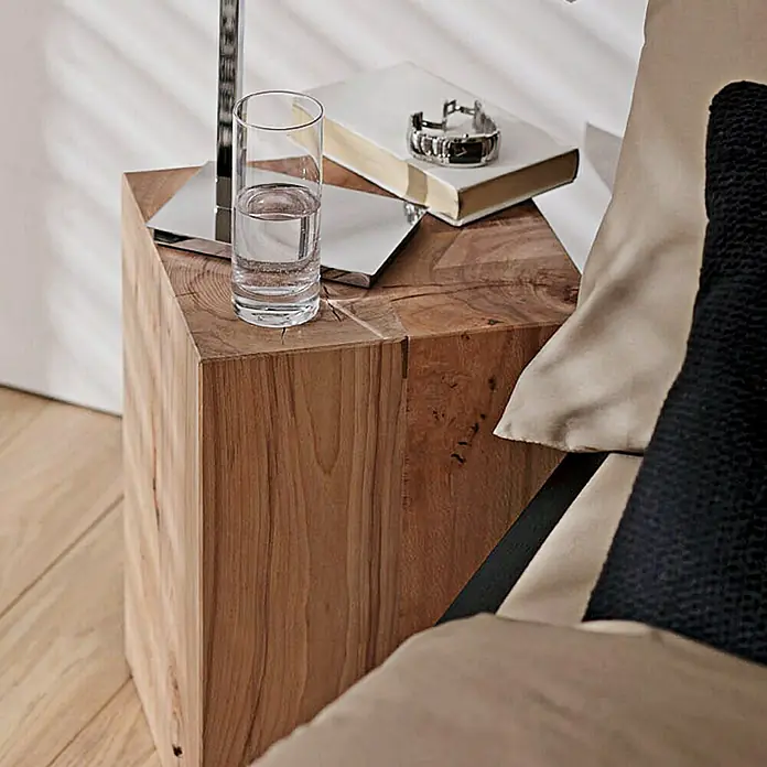 Noblewood MassivholzblockBuche, 30 x 30 x 45 cm - Ein rustikaler Nachttisch aus Holz mit einem Glas Wasser, einem Buch und einer Uhr darauf. Perfekt für ein gemütliches Schlafzimmerambiente.