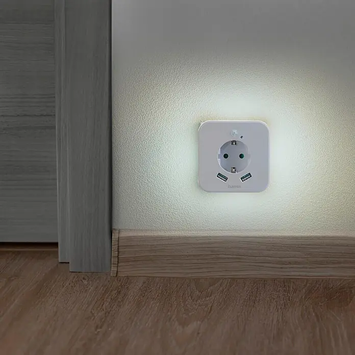Hama LED-Nachtlicht 00223507 mit Steckdose 2 USB-Ausgänge Bewegungsmelder Lichtsensor -  - Weißer Hama Wandadapter mit einer Steckdose, drei USB-Anschlüssen und integriertem Nachtlicht, sanft leuchtend an einer Wand.