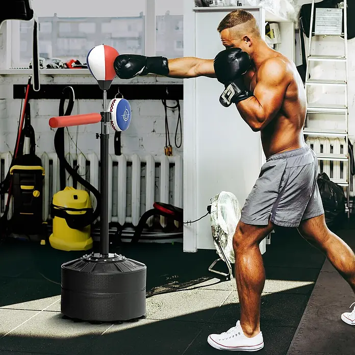 Sportnow Boxsack - Schwarz - Mann im Fitnessstudio boxt einen freistehenden Box-Reflexball mit schwarzem Standfuß, rot-weiß-blauem Speedball und blau-weißem Zielpolster.