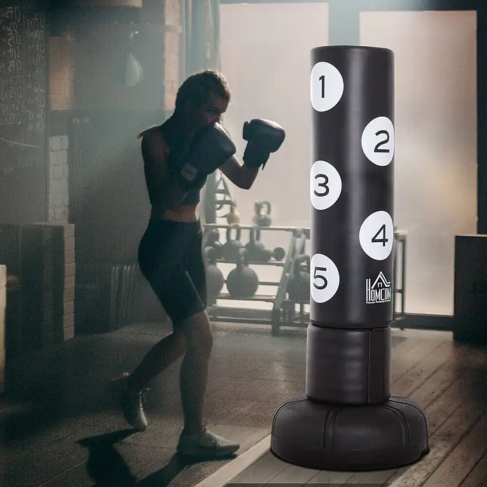 Homcom Boxsack - Schwarz - Schwarzer freistehender Boxsack mit nummerierten Zielen, von einem Boxer in einer Sporthalle verwendet.