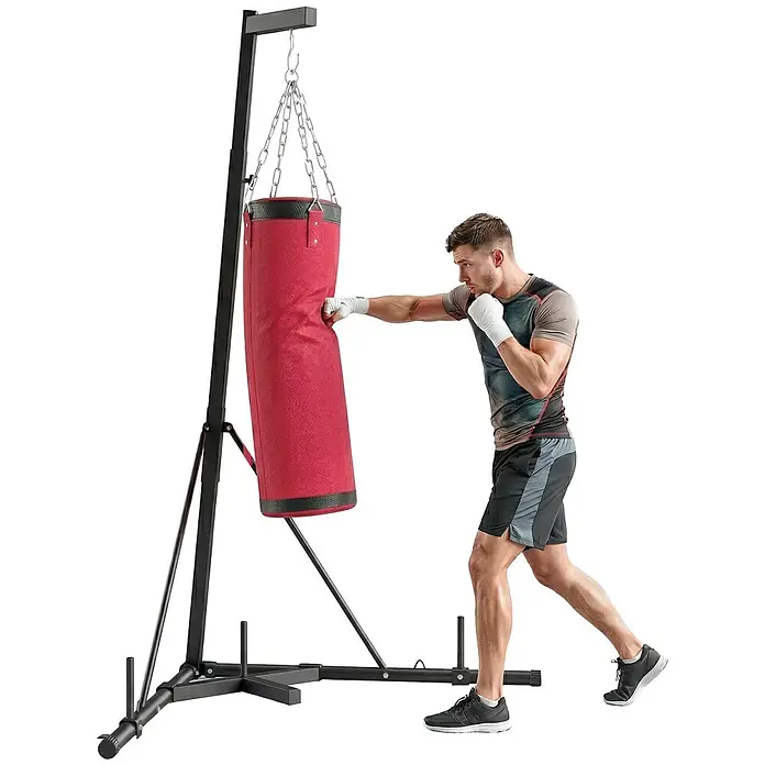 Sportnow Boxsack - Rot - Ein Mann schlägt auf einen roten Boxsack an einem schwarzen, freistehenden Metallständer für Boxtraining.