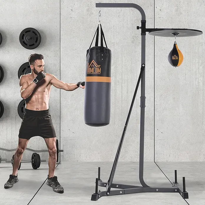 Homcom Boxsack - Schwarz - Grauer Boxständer mit schwarz-orangenem Sandsack und schwarz-gelbem Speedball. Ein Mann boxt am Sandsack.