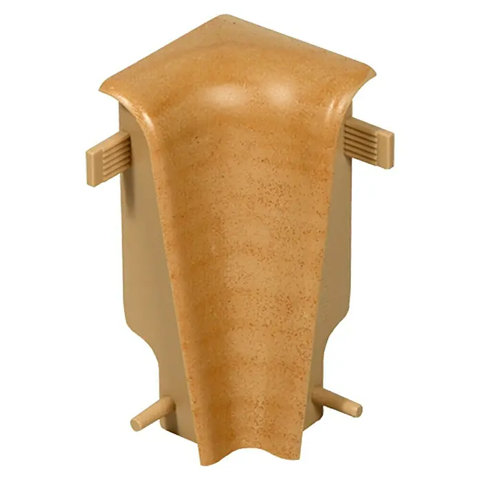 Profiles and more Innenecke FU60L - Birne golden, 2 Stk. - Nahaufnahme einer beigen Sockelleisten-Ecke mit abgerundeter Oberseite und seitlichen Befestigungsstiften für eine saubere Wandgestaltung.