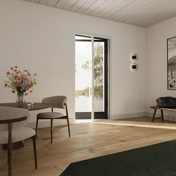 Cocoon Home Concepts Insektenschutz-Türplissee - B x H: 96 x 233 cm, Montage Insektengitter: Schrauben - Ein modernes Esszimmer mit rundem Holztisch, gepolsterten Stühlen, lebhaften Blumen und warmem Holzboden mit dunkelgrünem Teppich.