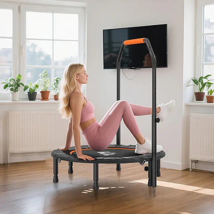 Homcom Rebounder - Stahl, Schwarz - Eine Frau in rosa Sportkleidung macht Beinheben auf einem schwarzen Minitrampolin mit orangem verstellbarem Haltegriff in einem hellen Raum.