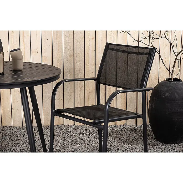Ebuy24 Gartentisch-Set BreakSantorini - Gesamtumfang: 3 -tlg., L x B x H: 90 x 90 x 74 cm, Ø x H: 90 x 74 cm, AintwoodAluminium, Stapelbar - Schwarzer Metall- und Netzstuhl mit passendem Tisch auf Kies vor Holzwand.