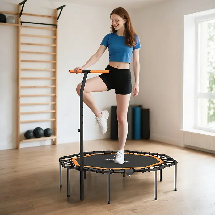 Sportnow Rebounder - Stahl, Schwarz, Orange - Frau nutzt ein schwarz-oranges Minitrampolin mit Haltegriff in einem Fitnessraum.