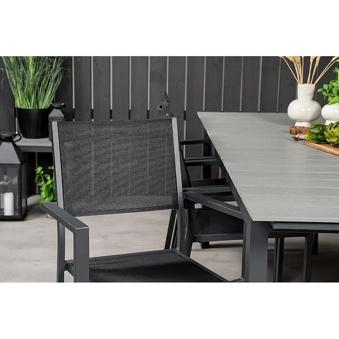 Ebuy24 Gartentisch-Set Levels - Gesamtumfang: 7 -tlg., L x B x H: 229 x 100 x 74 cm, Ø x H: 229 x 74 cm, Aintwood, Stapelbar - Hellgrauer Gartentisch und dunkelgraue Stühle mit schwarzem Netzgewebe, auf einer Terrasse.
