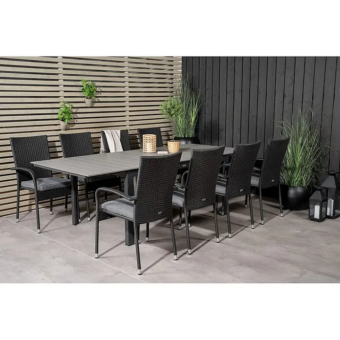 Ebuy24 Gartentisch-Set Levels - Gesamtumfang: 9 -tlg., L x B x H: 160 x 100 x 75 cm, Ø x H: 100 x 75 cm, Rattan, Stahl Aintwood, Aluminium, Stapelbar - Garten-Essgruppe mit grauem Latten-Tisch und schwarzen Korbsesseln mit grauen Kissen auf einer Terrasse.