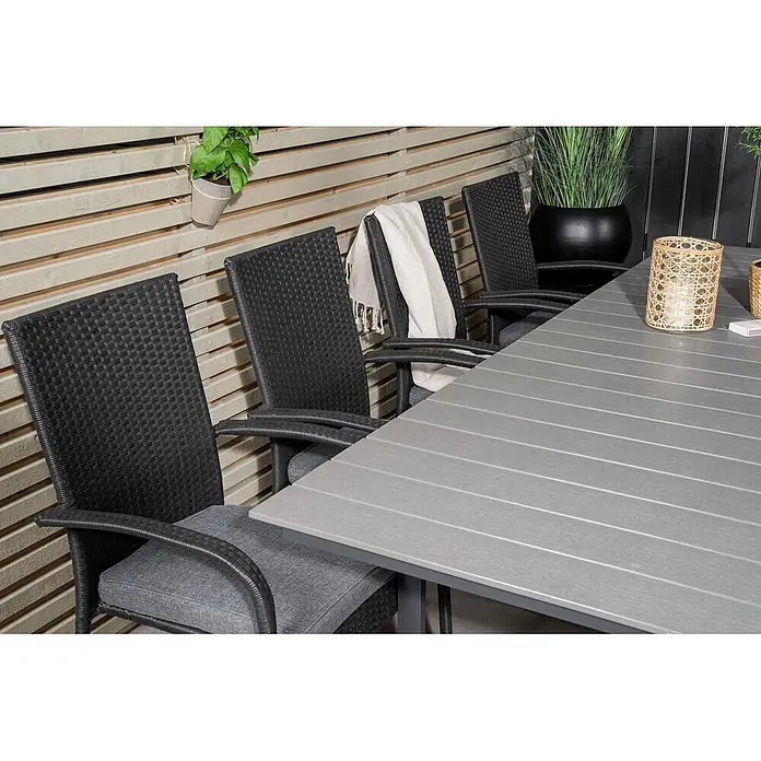 Ebuy24 Gartentisch-Set Levels - Gesamtumfang: 9 -tlg., L x B x H: 160 x 100 x 75 cm, Ø x H: 100 x 75 cm, Rattan, Stahl Aintwood, Aluminium, Stapelbar - Gartengarnitur mit grauem Latten-Tisch und schwarzen Korbstühlen mit grauen Kissen auf einer Terrasse.