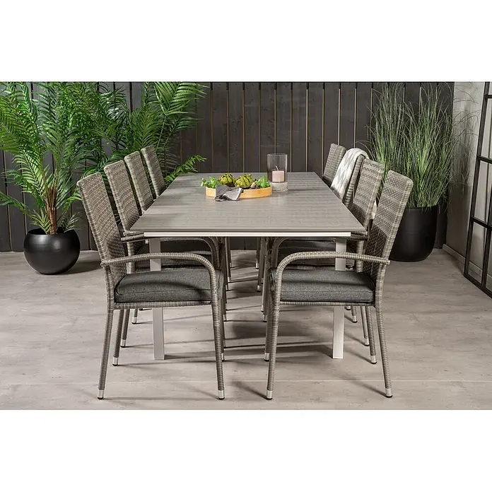 Ebuy24 Gartentisch-Set Levels - Gesamtumfang: 9 -tlg., L x B x H: 100 x 160 x 75 cm, Ø x H: 100 x 75 cm, Rattan, Stahl Aintwood, Aluminium, Stapelbar - Outdoor-Essgruppe mit grauem Tisch und acht grauen Korbsesseln mit dunklen Kissen auf einer Terrasse.
