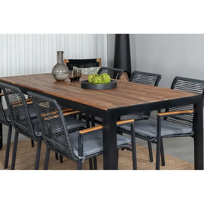 Ebuy24 Gartentisch-Set Bois - Gesamtumfang: 7 -tlg., L x B x H: 205 x 90 x 76 cm, Ø x H: 90 x 76 cm, 100 % Polyester, Holz, Rattan, Stahl Akazie, Aluminium, Stapelbar - Outdoor-Essgruppe mit Holzlamellentisch und schwarzem Metallgestell. Stühle mit schwarzen geflochtenen Rückenlehnen, Holzarmlehnen und grauen Kissen.