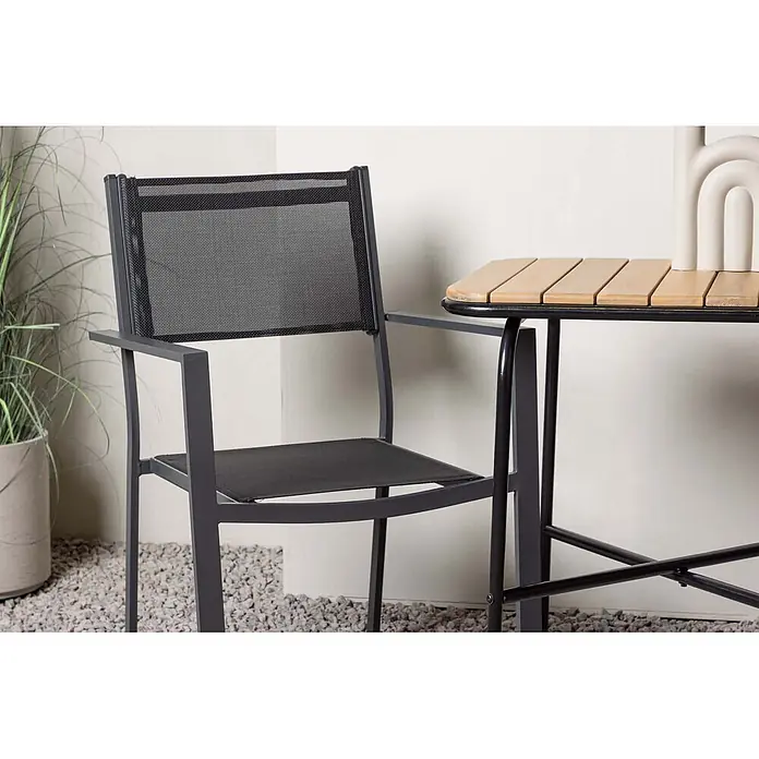 Ebuy24 Gartentisch-Set Holmbeck - Gesamtumfang: 3 -tlg., L x B x H: 70 x 88 x 74 cm, Ø x H: 88 x 74 cm, Textil Akazie, Stapelbar - Dunkelgrauer Metall-Outdoorstuhl mit schwarzem Netzgewebe und passendem Tisch mit Holzlamellen auf Kies.