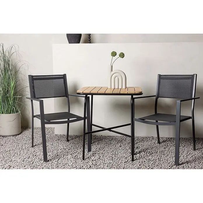 Ebuy24 Gartentisch-Set Holmbeck - Gesamtumfang: 3 -tlg., L x B x H: 70 x 88 x 74 cm, Ø x H: 88 x 74 cm, Textil Akazie, Stapelbar - Zwei dunkelgraue Outdoor-Stühle mit Netzsitzen und -lehnen flankieren einen kleinen Outdoor-Tisch mit Holzlattenplatte und schwarzem Metallgestell auf Kies.