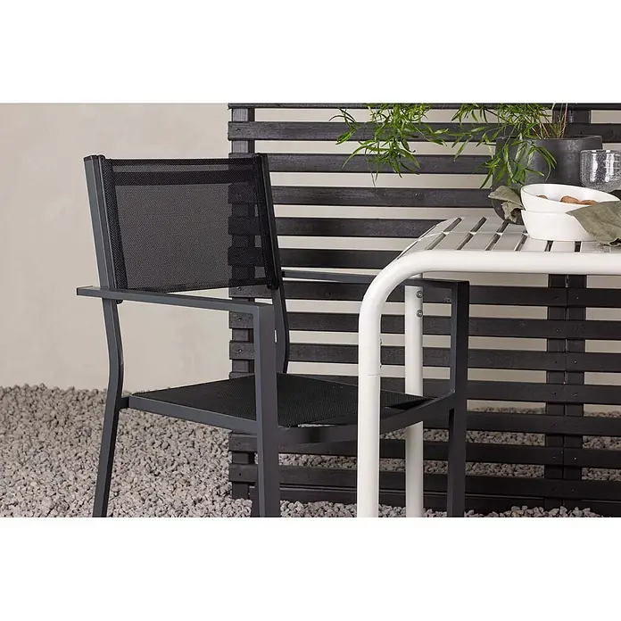 Ebuy24 Gartentisch-Set Borneo - Gesamtumfang: 3 -tlg., L x B x H: 70 x 70 x 75 cm, Ø x H: 70 x 75 cm, Textil Aluminum, Stapelbar - Dunkelgrauer Metall-Gartenstuhl mit schwarzer Netzbespannung neben einem weißen Lamellentisch auf einer Terrasse.