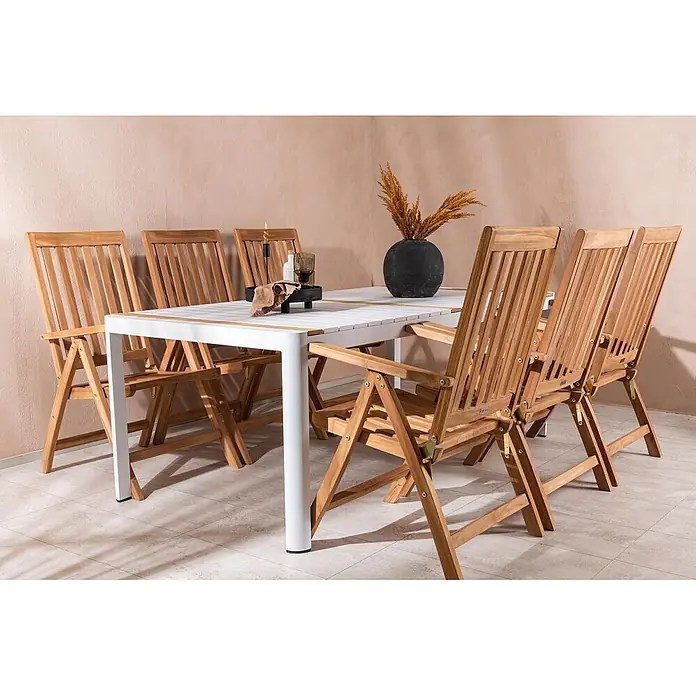 Ebuy24 Gartentisch-Set Togo - Gesamtumfang: 7 -tlg., L x B x H: 200 x 75 x 100 cm, Ø x H: 200 x 100 cm, Tisch: Aluminum,Teak Stuhl: Teak, Stapelbar - Eine Outdoor-Essgruppe mit weißem Tisch mit Holzlatten und Klappstühlen aus Naturholz auf einer Terrasse.