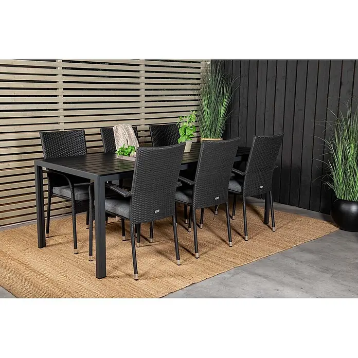 Ebuy24 Gartentisch-Set Break - Gesamtumfang: 7 -tlg., L x B x H: 205 x 90 x 74 cm, Ø x H: 90 x 74 cm, Korbmöbel, Nonwood, Stapelbar - Outdoor-Essgruppe: dunkelgrauer Tisch, sechs schwarze Korbstühle mit grauen Kissen, auf gewebtem Teppich auf Terrasse.