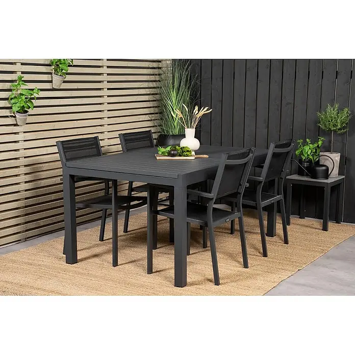 Ebuy24 Gartentisch-Set Marbella - Gesamtumfang: 5 -tlg., L x B x H: 100 x 160 x 75 cm, Ø x H: 100 x 75 cm, Aluminium, Stapelbar - Dunkelgraue Outdoor-Essgruppe mit rechteckigem Tisch und sechs Stühlen auf einem strukturierten Teppich.