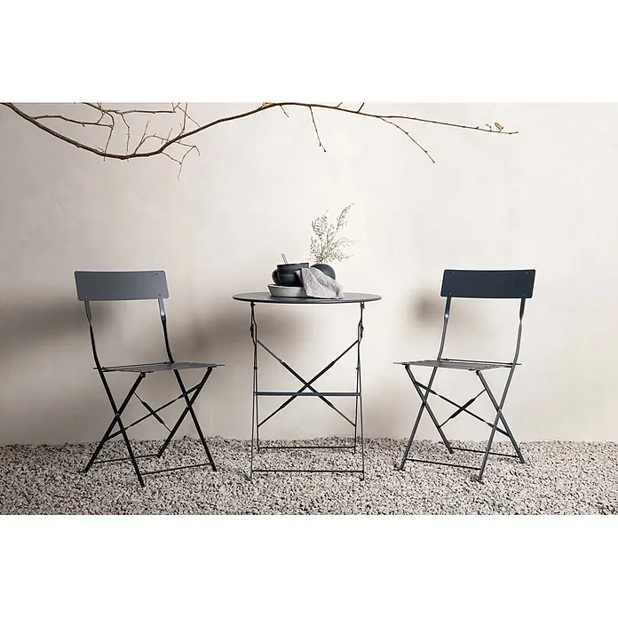 Ebuy24 Gartentisch-Set Marseille - Gesamtumfang: 3 -tlg., L x B x H: 60 x 60 x 71 cm, Ø x H: 60 x 71 cm, Stahl, Stapelbar - Dunkelgraues Metall-Bistroset mit Tisch und zwei Klappstühlen auf einem Kies-Patio, dekoriert.