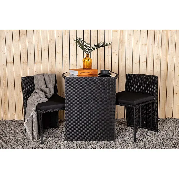 Ebuy24 Gartentisch-Set Savanna - Gesamtumfang: 3 -tlg., L x B x H: 50 x 66 x 75 cm, Ø x H: 50 x 75 cm, Kunststoff, Metall, Ausziehbar - Ein schwarzer Rattan-Bartisch mit Glasplatte und zwei passenden Barstühlen mit schwarzen Kissen, in einem Outdoor-Setting arrangiert.
