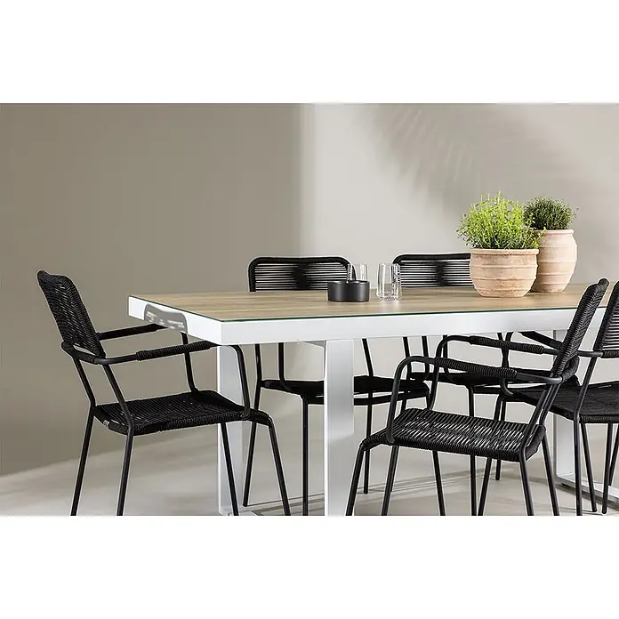 Ebuy24 Gartentisch-Set Merlo - Gesamtumfang: 7 -tlg., L x B x H: 90 x 200 x 75 cm, Ø x H: 90 x 75 cm, Aluminium Polyesterseil Stahl, Stapelbar - Outdoor-Essgruppe mit rechteckigem weiß-holz Tisch und schwarzen Seilgeflechtstühlen. Zwei Topfpflanzen auf dem Tisch.