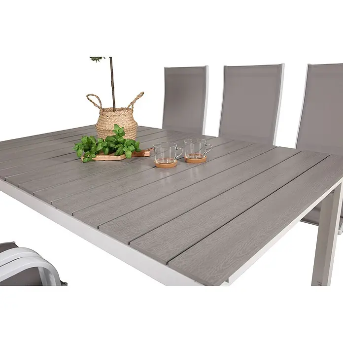 Ebuy24 Gartentisch-Set Levels - Gesamtumfang: 7 -tlg., L x B x H: 100 x 160 x 75 cm, Ø x H: 100 x 75 cm, 30 % Polyester, 70 % PVC, Aluminium, Textil Aintwood, Aluminium, Stapelbar - Grauer Latten-Gartentisch mit weißem Gestell und passenden Stühlen. Dekoriert mit einer Pflanze, Kräutern und zwei Glastassen.