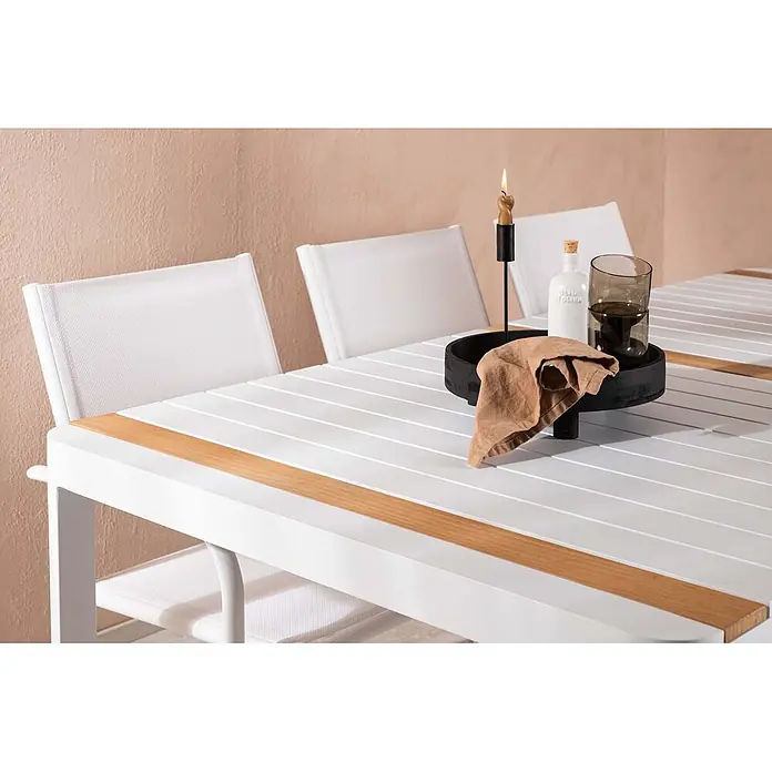 Ebuy24 Gartentisch-Set Togo - Gesamtumfang: 7 -tlg., L x B x H: 100 x 200 x 75 cm, Ø x H: 100 x 75 cm, Aluminium, Stapelbar - Weißer Gartentisch mit Holzdetails und weißen Stühlen, dekoriert mit Tablett, Kerze, Flasche und Gläsern.