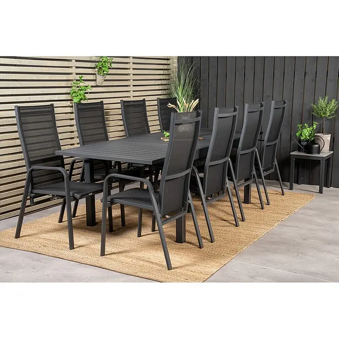 Ebuy24 Gartentisch-Set Marbella - Gesamtumfang: 9 -tlg., L x B x H: 100 x 160 x 75 cm, Ø x H: 100 x 75 cm, 30 % Polyester, 70 % PVC, Aluminium, Textil Aluminium, Stapelbar - Graues Outdoor-Esstisch-Set mit Tisch und acht Stühlen mit schwarzem Sling-Stoff, auf beigem Teppich auf einer Terrasse.