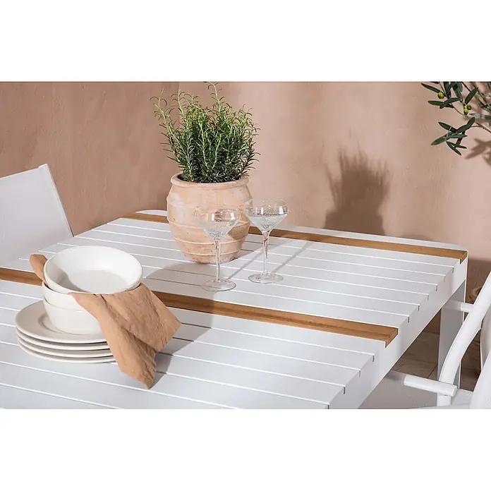 Ebuy24 Gartentisch-Set Togo - Gesamtumfang: 5 -tlg., L x B x H: 90 x 150 x 75 cm, Ø x H: 90 x 75 cm, Aluminium, Stapelbar - Weißer Outdoor-Esstisch mit Holzapplikationen, gedeckt mit Geschirr, Gläsern und einer Topfpflanze.
