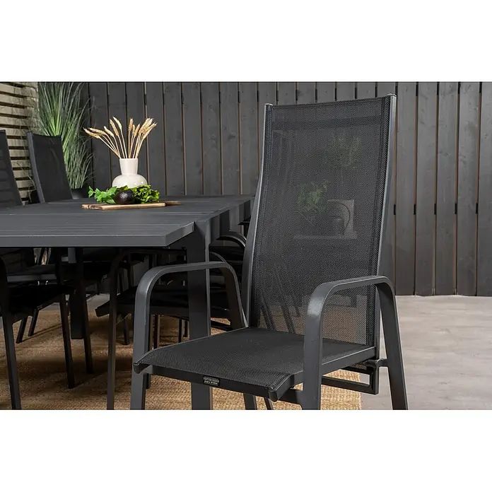 Ebuy24 Gartentisch-Set Marbella - Gesamtumfang: 9 -tlg., L x B x H: 100 x 160 x 75 cm, Ø x H: 100 x 75 cm, 30 % Polyester, 70 % PVC, Aluminium, Textil Aluminium, Stapelbar - Dunkelgrauer Outdoor-Esstischstuhl mit Netzgewebe, Teil einer Essgruppe auf einer Terrasse.