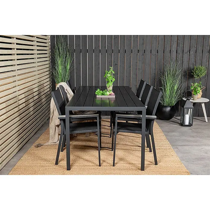 Ebuy24 Gartentisch-Set Break - Gesamtumfang: 7 -tlg., L x B x H: 205 x 90 x 74 cm, Ø x H: 90 x 74 cm, Aintwood Aluminium Textil, Stapelbar - Dunkelgraue/schwarze Outdoor-Esstischgruppe mit vier Stühlen auf einem geflochtenen Teppich, auf einer Terrasse.