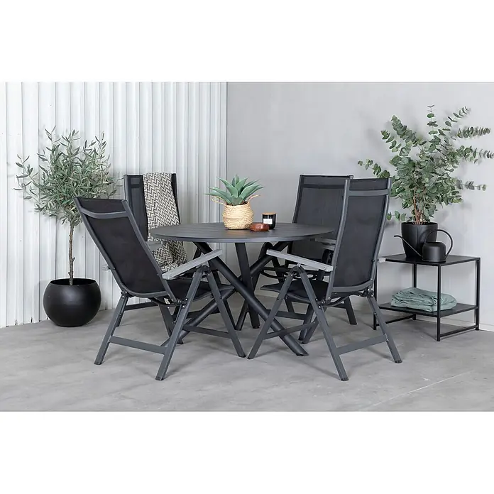 Ebuy24 Gartentisch-Set Alma - Gesamtumfang: 7 -tlg., L x B x H: 120 x 120 x 75 cm, Ø x H: 120 x 75 cm, Aintwood, Aluminium, Textil Aluminium, Stapelbar - Graues Metall- und schwarzes Netz-Outdoor-Esstisch-Set mit rundem Tisch und vier Stühlen, auf einer Terrasse platziert.