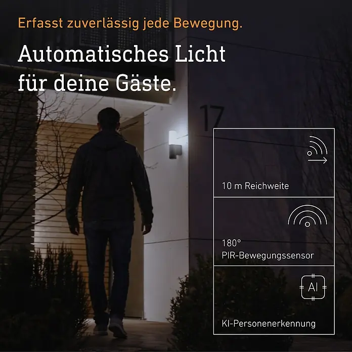 Steinel LED-Sensor-Außenwandleuchte L 625 CAM SC - 14 W, L x B x H: 13,1 x 7,8 x 30,5 cm, Anthrazit/Weiß, Warmweiß - Mann geht auf Haus zu, beleuchtet von einem automatischen Außenlicht mit Bewegungsmelder und KI-Personenerkennung für Gäste.
