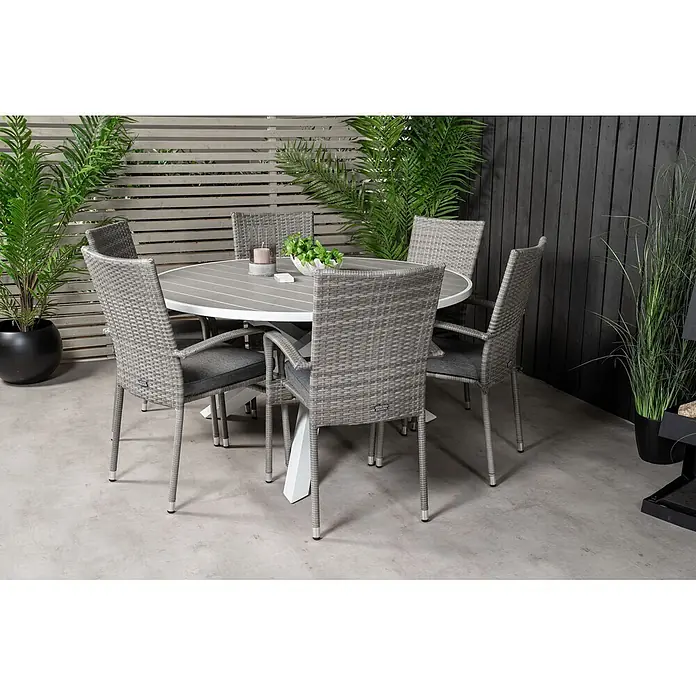 Ebuy24 Gartentisch-Set Parma - Gesamtumfang: 7 -tlg., L x B x H: 140 x 140 x 73 cm, Ø x H: 140 x 73 cm, Rattan, Stahl Aintwood, Aluminium, Stapelbar - Outdoor-Essgruppe mit rundem Tisch mit grauer Lattenplatte und weißem Fuß, umgeben von sechs grauen Rattan-Stühlen mit dunkelgrauen Kissen.
