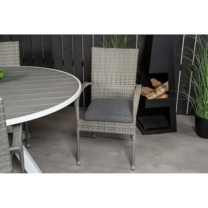 Ebuy24 Gartentisch-Set Parma - Gesamtumfang: 7 -tlg., L x B x H: 140 x 140 x 73 cm, Ø x H: 140 x 73 cm, Rattan, Stahl Aintwood, Aluminium, Stapelbar - Grauer Outdoor-Esszimmerstuhl aus Rattan mit grauem Kissen neben einem passenden Tisch.
