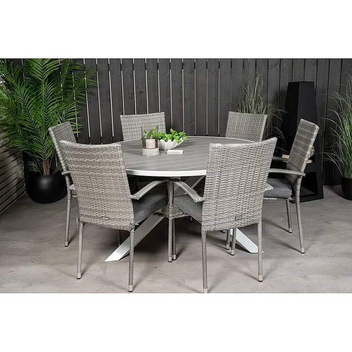 Ebuy24 Gartentisch-Set Parma - Gesamtumfang: 7 -tlg., L x B x H: 140 x 140 x 73 cm, Ø x H: 140 x 73 cm, Rattan, Stahl Aintwood, Aluminium, Stapelbar - Runder grauer Esstisch für den Außenbereich mit sechs passenden Korbstühlen und grauen Kissen auf einer Terrasse.