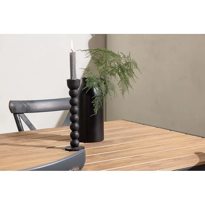 Ebuy24 Gartentisch-Set Break - Gesamtumfang: 5 -tlg., L x B x H: 90 x 150 x 74 cm, Ø x H: 90 x 74 cm, Aluminium, Kunststoff, Stapelbar - Schwarzer kugelförmiger Kerzenständer mit brennender grauer Kerze auf einem Holztisch, neben einer Vase mit Grün.