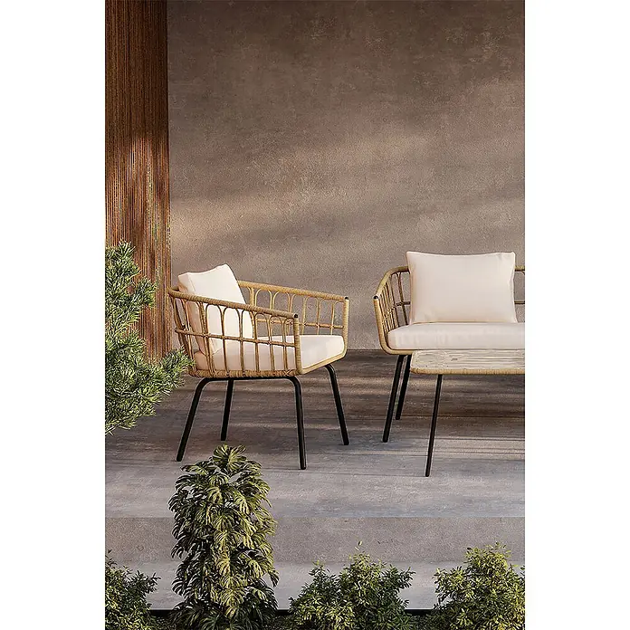 Ebuy24 Loungemöbel-Set Ortigia - 4 -tlg., Stahl, Natur - Zwei Outdoor-Stühle und ein Tisch aus natürlichem Rattan mit schwarzen Beinen und weißen Kissen auf einer Terrasse.