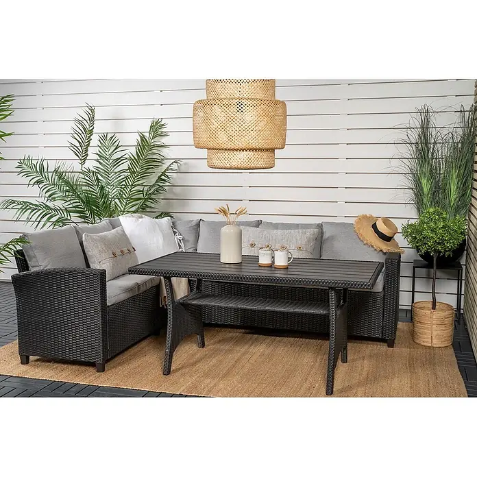Ebuy24 Loungemöbel-Set Brentwood - 2 -tlg., Holz Korbmöbel Polyester, Schwarz - Schwarzes Rattan-Loungesofa mit grauen Kissen und passendem Tisch auf einer Außenterrasse.