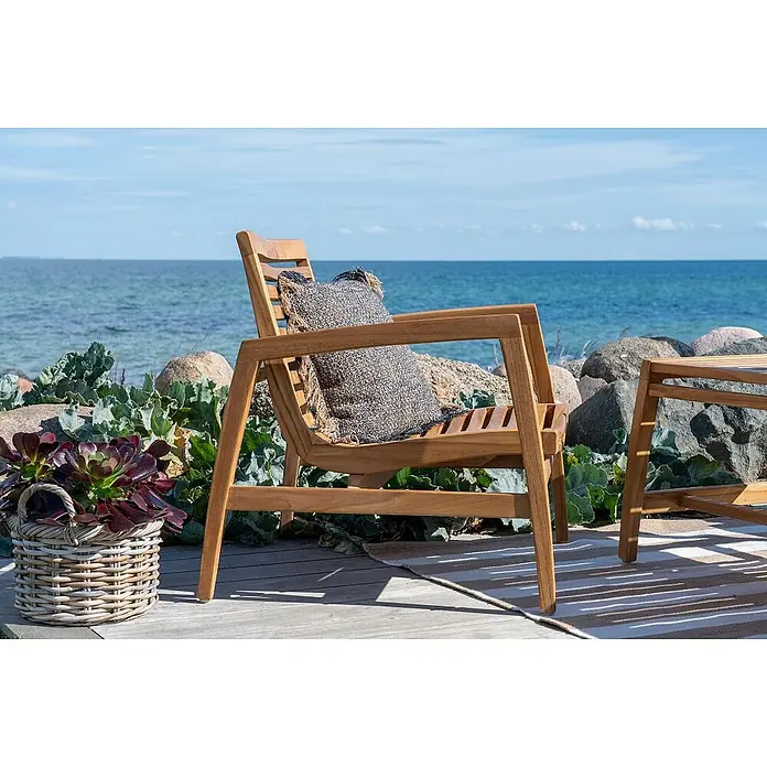 Ebuy24 Loungemöbel-Set Sanna - 4 -tlg., Teak, Teak - Teakholz-Gartensessel mit gemustertem Kissen auf einer Terrasse am Meer.
