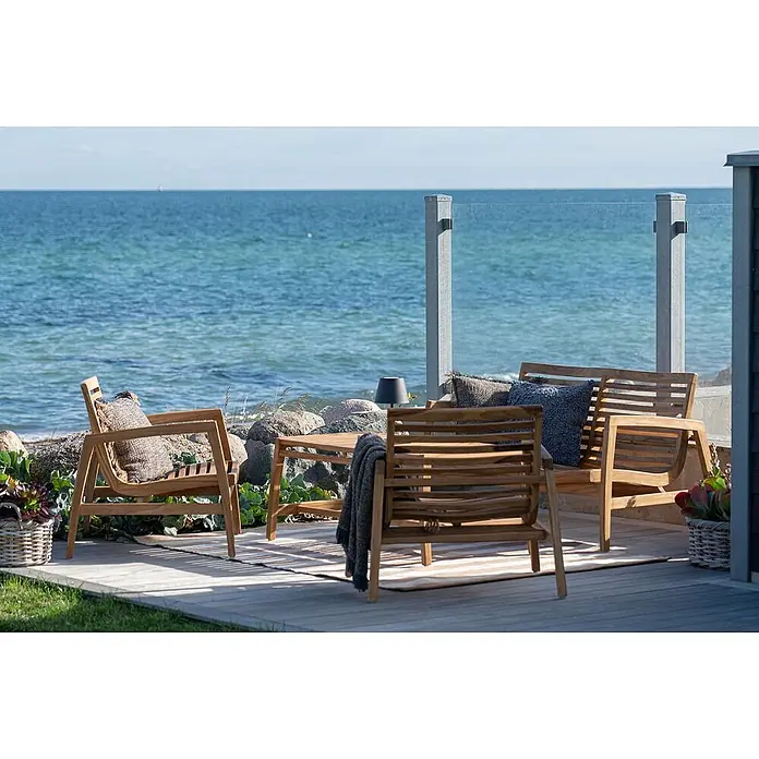 Ebuy24 Loungemöbel-Set Sanna - 4 -tlg., Teak, Teak - Hölzernes Outdoor-Lounge-Set: Stühle, Tisch, auf einer Terrasse am Meer.