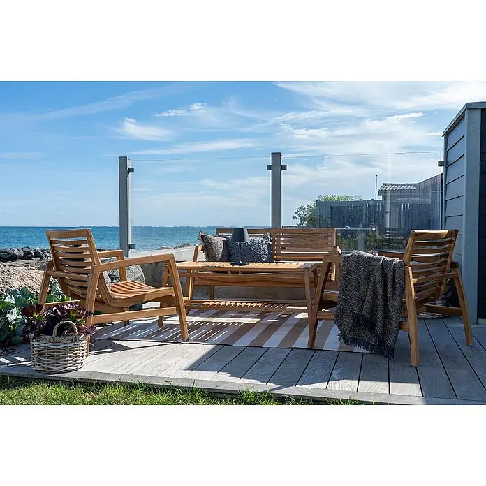 Ebuy24 Loungemöbel-Set Sanna - 4 -tlg., Teak, Teak - Teak-Gartenmöbelset (zwei Stühle, Sofa, Couchtisch) auf einer Terrasse am Meer, mit Kissen dekoriert.