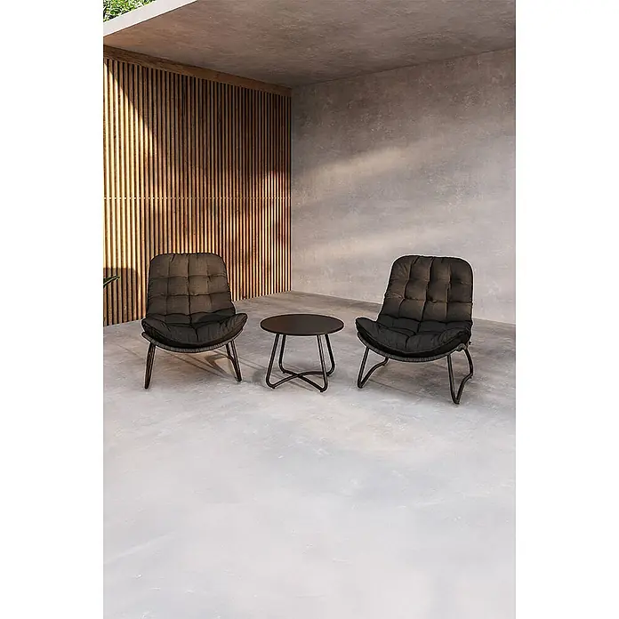 Ebuy24 Loungemöbel-Set Cala - 3 -tlg., Stahl, Anthrazit - Zwei schwarze gepolsterte Loungesessel und ein passender runder schwarzer Beistelltisch auf einer Betonterrasse mit Holzlamellenwand.