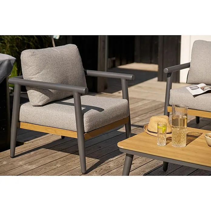 Ebuy24 Loungemöbel-Set Camilla - 4 -tlg., Nonwood (PE), Aluminium, Polyester, Graubeige - Zwei Outdoor-Sessel mit grauen Kissen, grauen Rahmen und Holzdetails, neben einem passenden Couchtisch auf einer Terrasse.