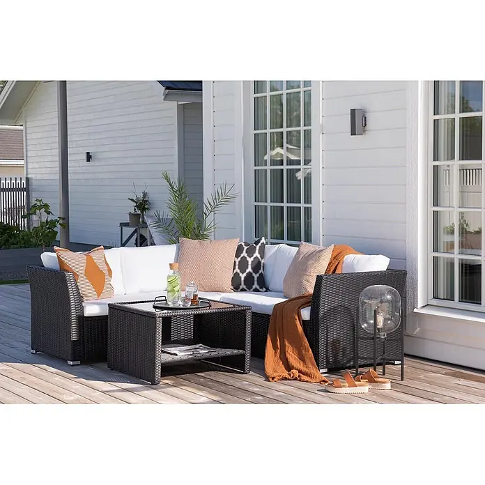 Ebuy24 Loungemöbel-Set Haiti - 2 -tlg., Glas Stahl Korbmöbel Polyester Schaum, Weiß - Dunkles Outdoor-Sofa-Set aus Polyrattan mit weißen Kissen und passendem Couchtisch auf Holzterrasse.