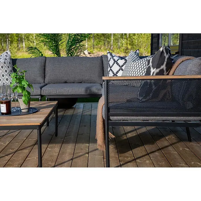 Ebuy24 Loungemöbel-Set Nettan - 2 -tlg., Stahl Teak, Schwarz - Gartenmöbel-Set: graues Stoffsofa, schwarzer Metall-Sessel mit Holzarmlehne und passender Holztisch auf einer Terrasse.